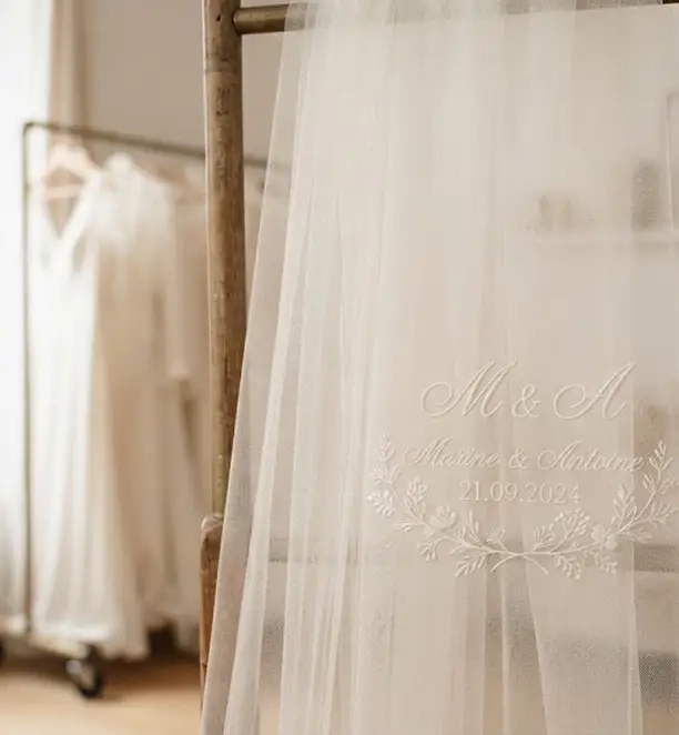 mains présentant une broderie de mariage soignée sur un établi
